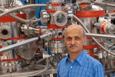 Senior Research Scientist Jagadeesh Moodera poses in front of a molecular beam epitaxy system