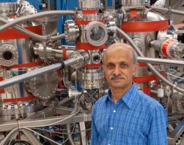 Senior Research Scientist Jagadeesh Moodera poses in front of a molecular beam epitaxy system
