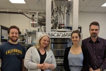 Four team members standing in front of ABRACADABRA, the instrument used to detect axions.