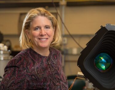 Jacqueline Hewitt stands with a prototype of one of the four cameras aboard the Transiting Exoplanet Satellite Survey (TESS) instrument.