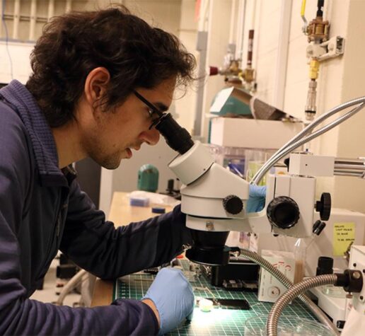 Photo of a man looking into a microscope in a laboratory