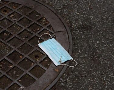 Discarded blue medical mask laying on ground