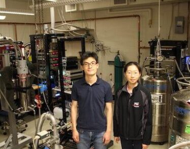 Physics postdoc and grad student stand in MIT lab.