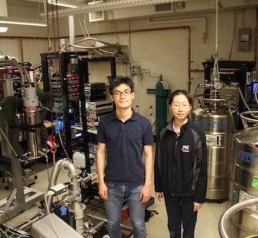 Physics postdoc and grad student stand in MIT lab.