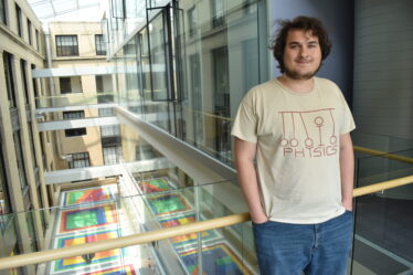 Senior Thomas Bergamaschi leans on a railing overlooking an indoor courtyard with a colorful floor