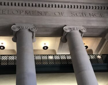 Photo of columns and balconies in MIT Lobby 7 with the etched words 