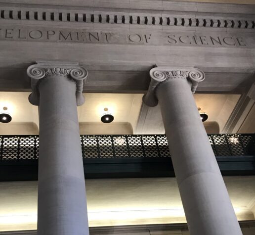 Photo of columns and balconies in MIT Lobby 7 with the etched words 