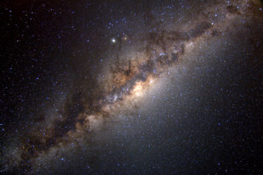 The Milky Way galaxy streaks diagonally across the image, glowing with celestial bodies.