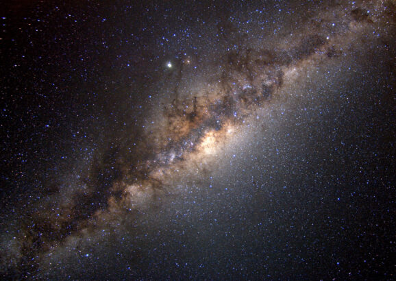 The Milky Way galaxy streaks diagonally across the image, glowing with celestial bodies.
