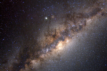 The Milky Way galaxy streaks diagonally across the image, glowing with celestial bodies.