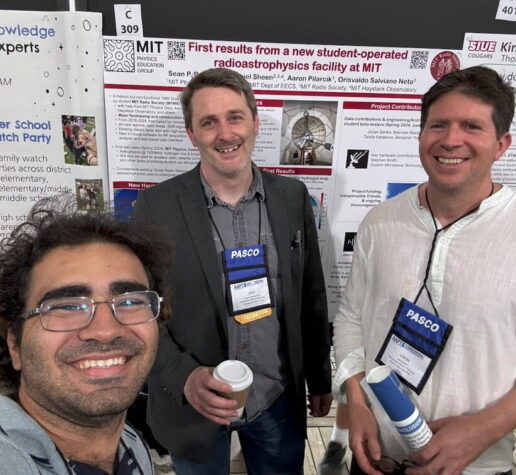 three people pose in front of physics posters