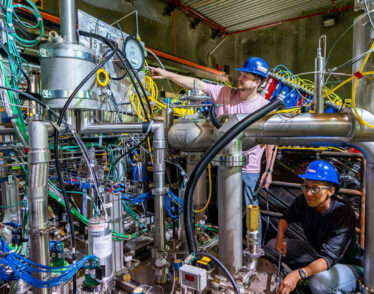 Two scientists in hard hats working on the 2x2 prototype detector for the DUNE near detector.