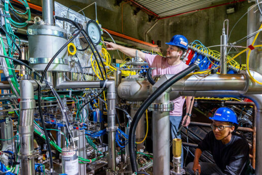 Two scientists in hard hats working on the 2x2 prototype detector for the DUNE near detector.