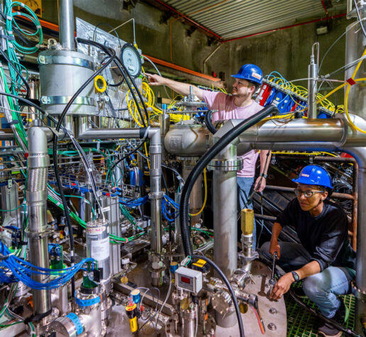 Two scientists in hard hats working on the 2x2 prototype detector for the DUNE near detector.