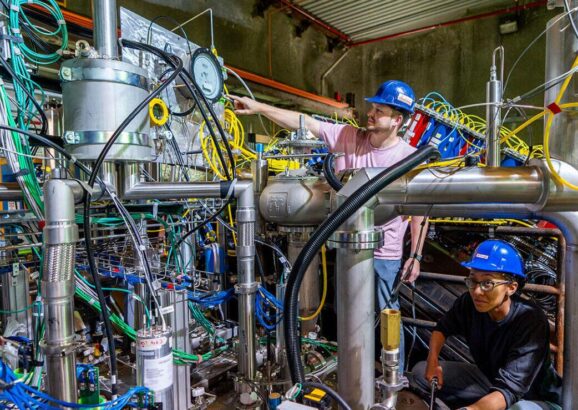 Two scientists in hard hats working on the 2x2 prototype detector for the DUNE near detector.