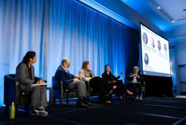 Five people sit on stage during a panel.