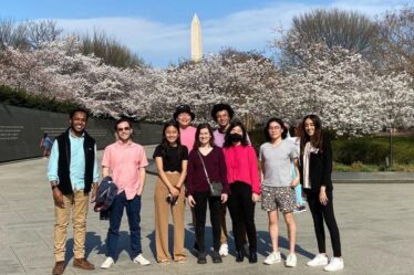 9 Students pose against a bank of cherry blossoms in front of the Washington Monument