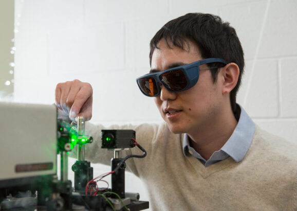 Professor Long Ju wears eye protection while working on experiment with lasers