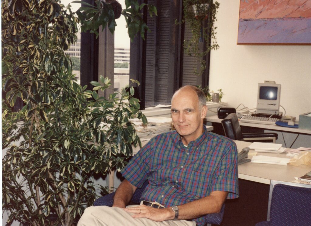 Hale Bradt sits beside large plant in his office