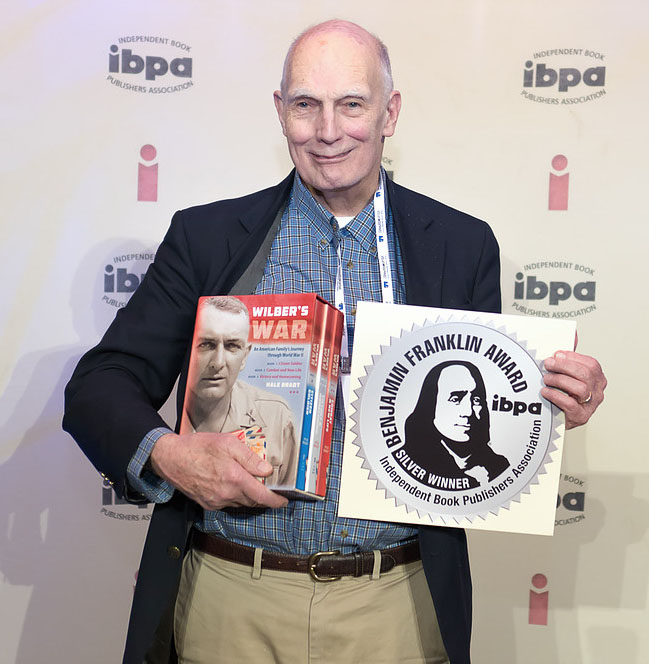 Hale Bradt poses holding his book, "Wilber's War", and his Benjamin Franklin Silver Winner Award from the IBPA