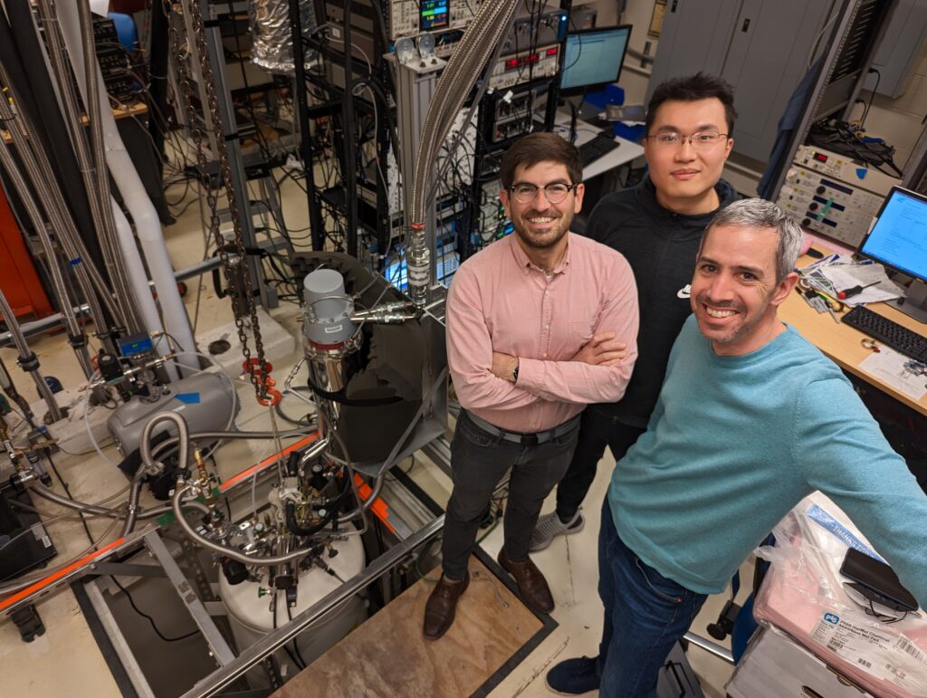 three men pose surrounded by scientific equipment