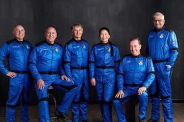 six people pose in blue jumpsuits