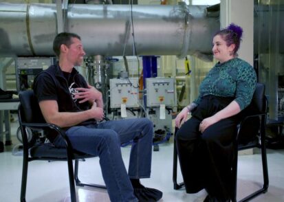 An image of two people sitting on chairs inside MIT LIGO Lab.