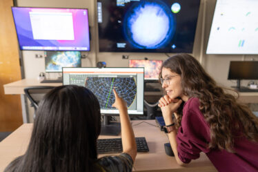 students confer in front of an array of monitors