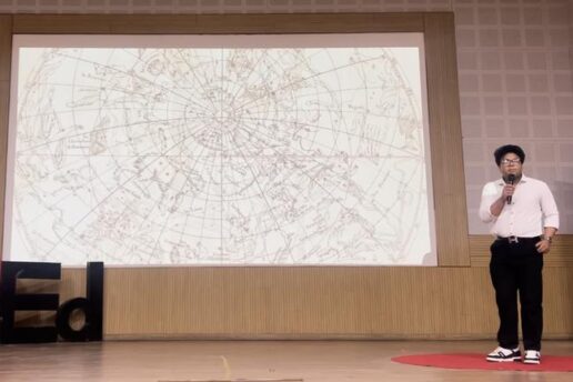 Vivan Mirchandani speaks in front of a screen, which shows graphics of constellations. A