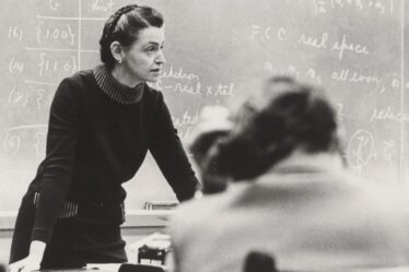 black and white image of Milliie Dresselhaus leaning forward on a desk in front of a chalkboard