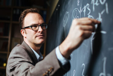 Jesse Thaler writes on blackboard