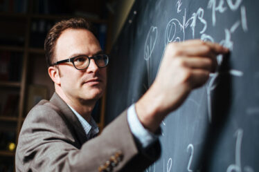 Jesse Thaler writes on blackboard