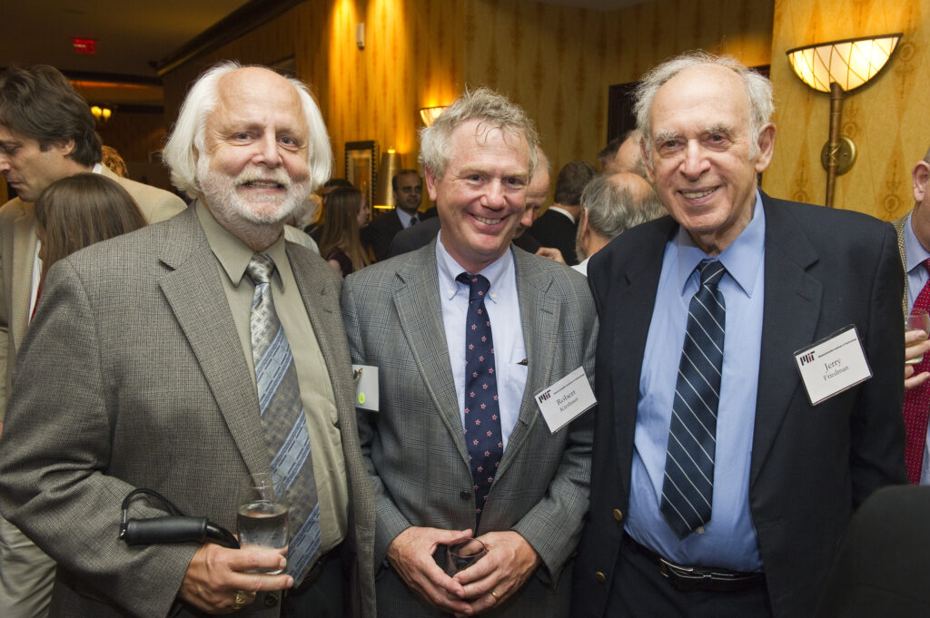 three men in suits stand together