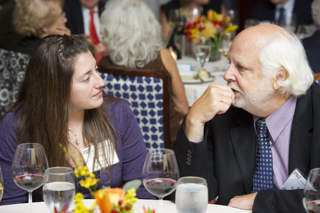 Two people wearing MIT nametags conversing at a formal banquet table