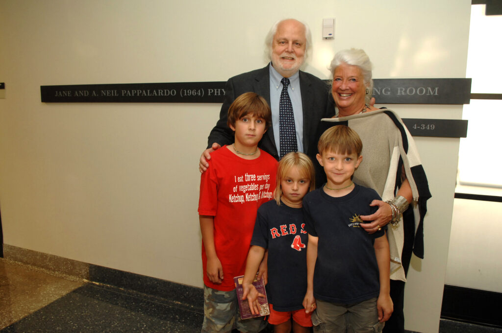 Neil and Jane Pappalardo standing with three grandchildren in front of a dedicated room sign at the Green Center.