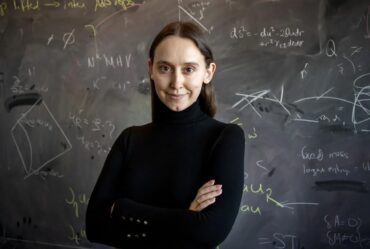 woman poses in front of blackboard