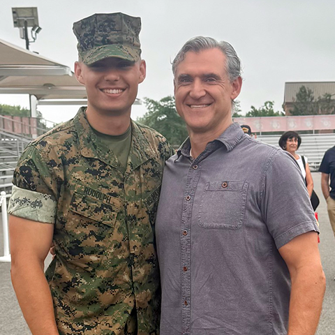 younger man in army fatigues poses with older man