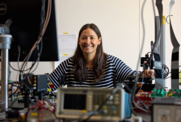 woman standing over equipment in lab