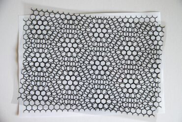 Two slightly rotated black hexagonal lattice sheets creating a moiré pattern over a white background.
