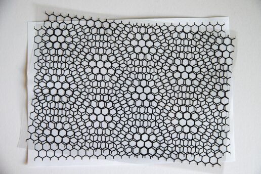 Two slightly rotated black hexagonal lattice sheets creating a moiré pattern over a white background.
