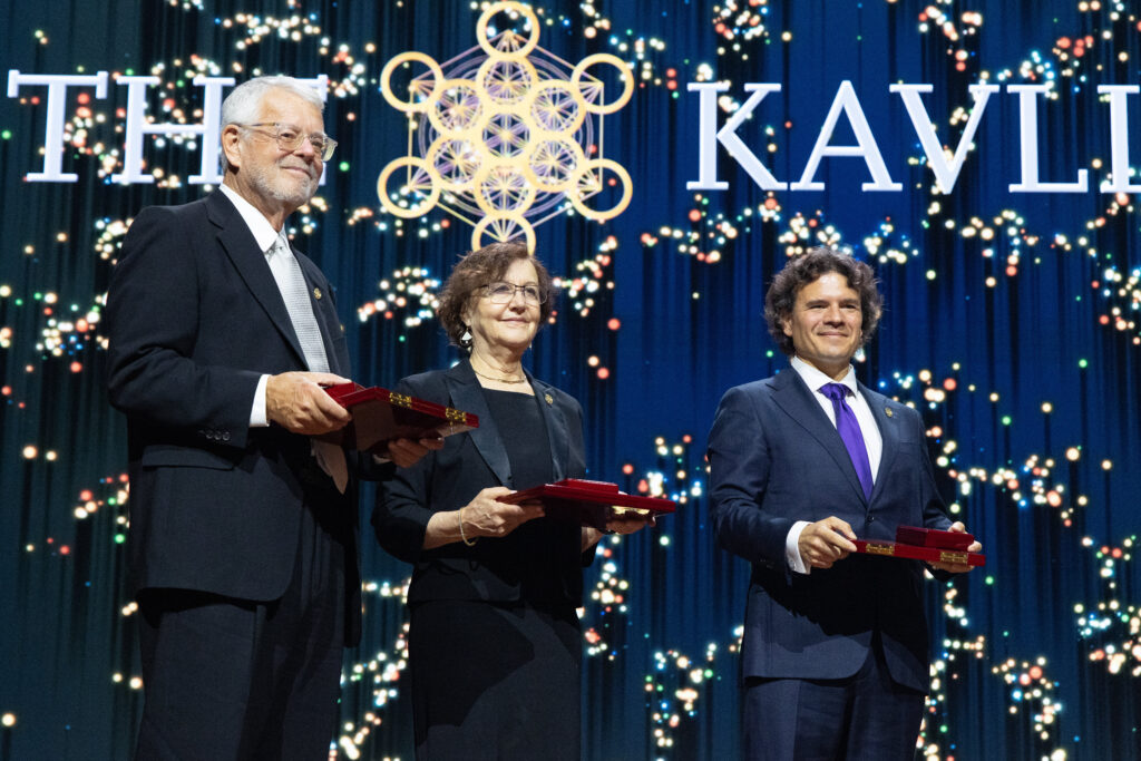 Three 2026 Kavli Prize laureates holding red award cases on stage.