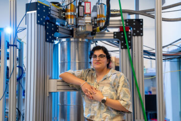 Faith Reyes stands in front of a large device in the lab.