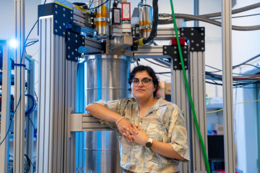 Faith Reyes stands in front of a large device in the lab.