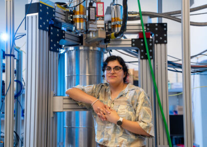 Faith Reyes stands in front of a large device in the lab.